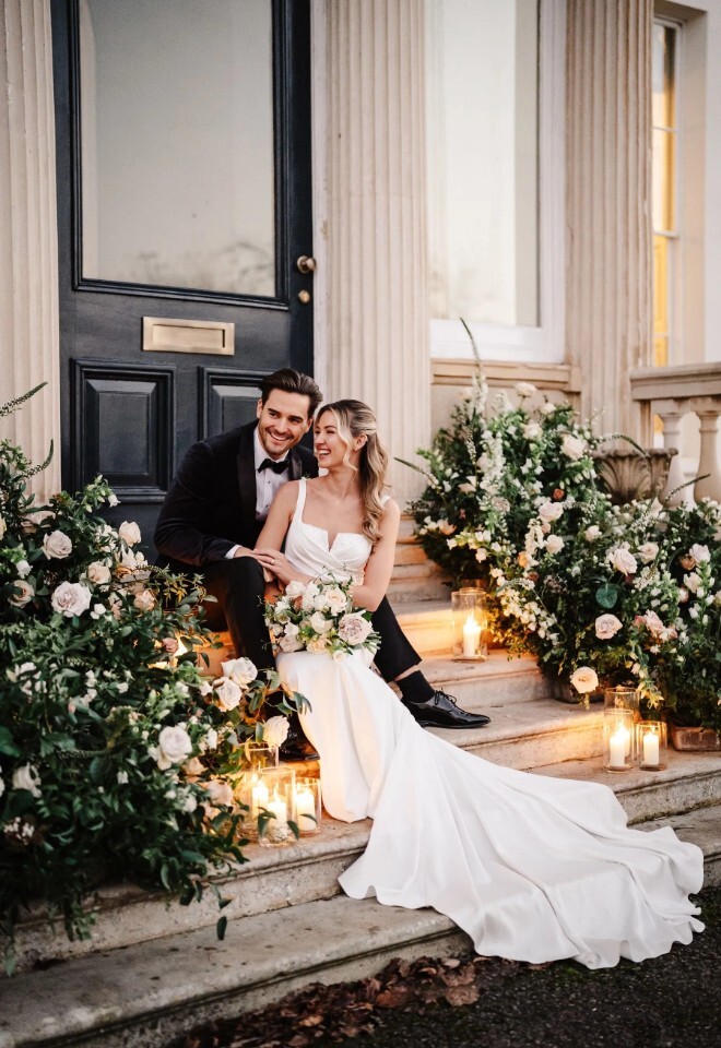 Bride and groom seated on the steps of Henlade House wedding venue in Somerset, surrounded by florals and candlelight.
