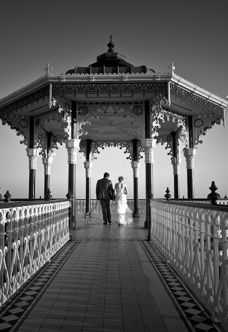 Black and white wedding photography bride and groom walking with dog on Brighton pier
