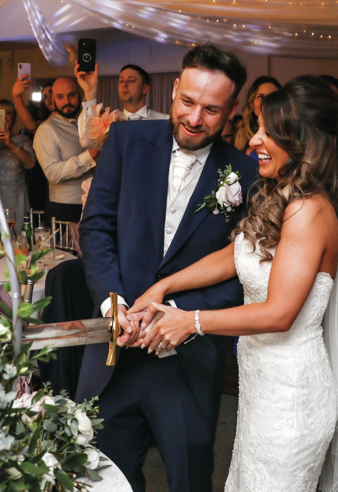 bride & groom cutting wedding cake with a sword at Stirk House
