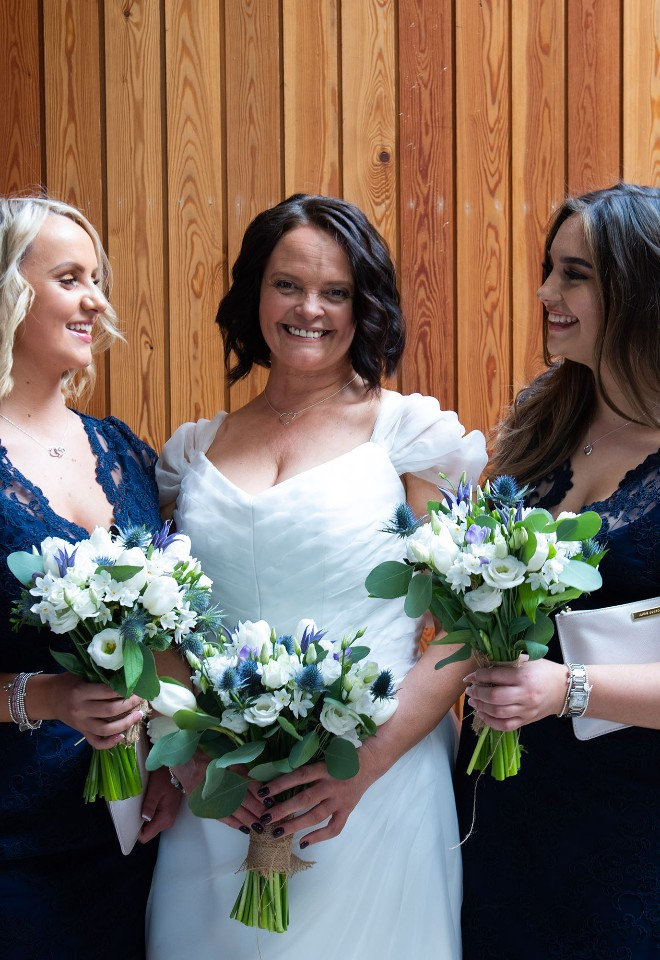 Two bridesmaids in navy look at their bride, smiling, at The Woodsman Restaurant in Stratford-upon-Avon