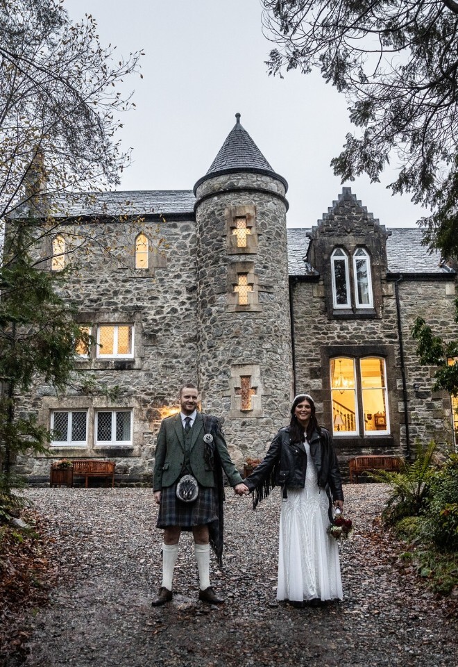 Bride and groom stand hand in hand outside the castle