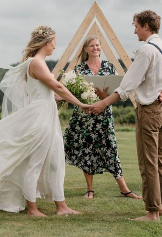 Young barefoot bride and groom with smiling celebrant