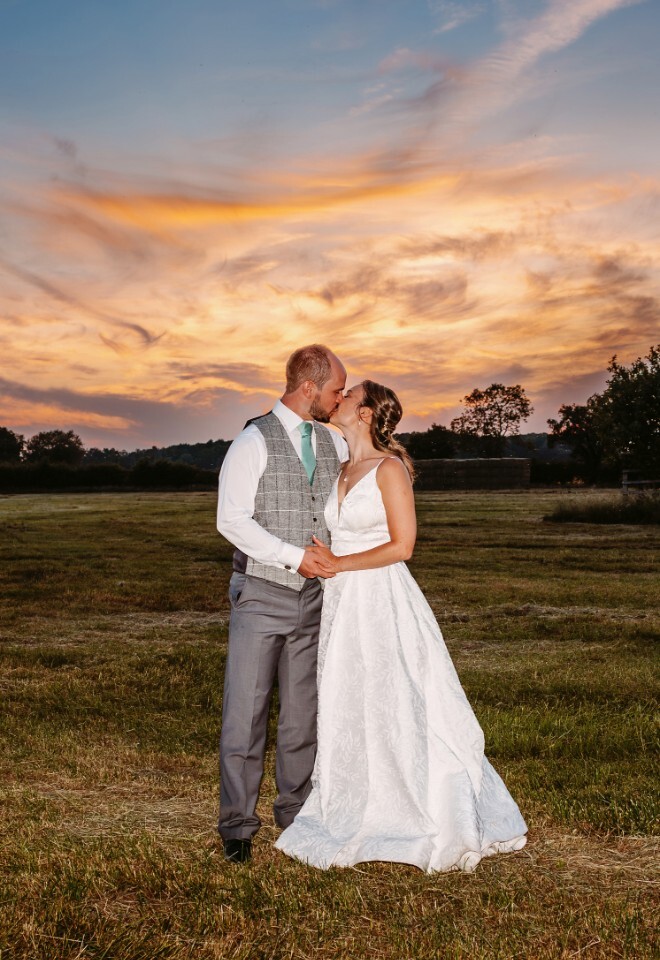 Couple kissing under stunning sunset sky at Caswell House wedding venue