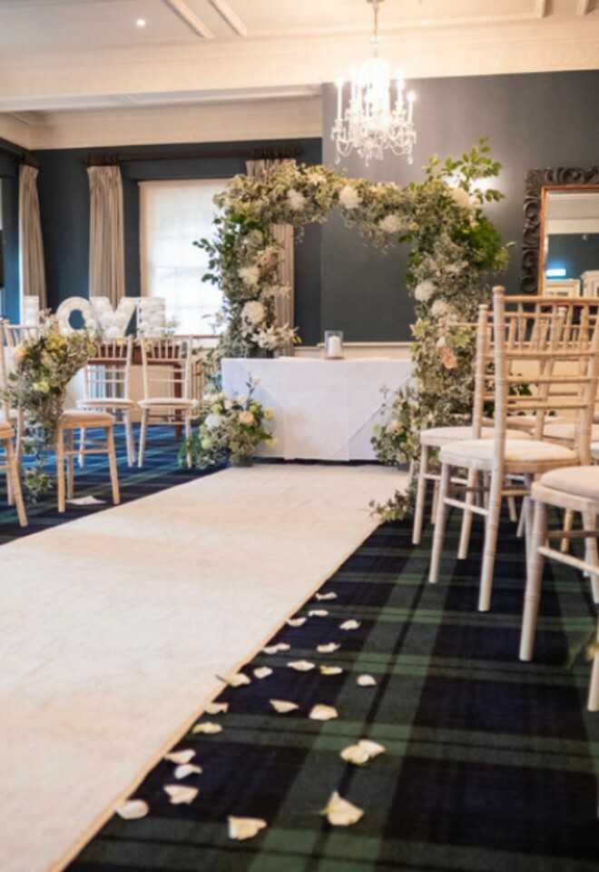 Wedding ceremony inside with ivory carpet and petals along the aisle
