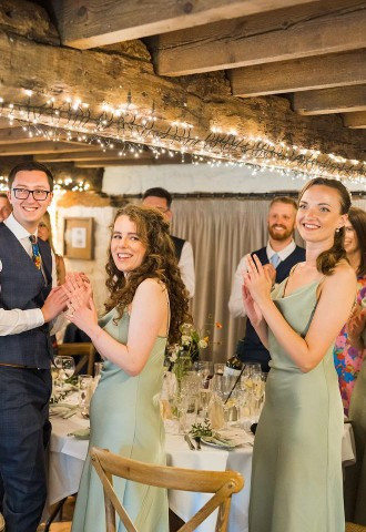 Wedding party clap as bride and groom walk into wedding breakfast