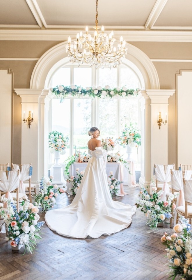 Bride in ceremony room, surrounded by florals at Glewstone Court