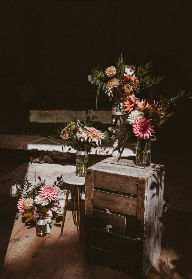 Wild Fig Flowers wedding floral display in Oxfordshire, featuring colourful pink, peach and white flowers arranged in glass jars on rustic wooden crates.