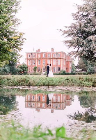 Bride and groom posing outside Chicheley Hall, Buckinghamshire