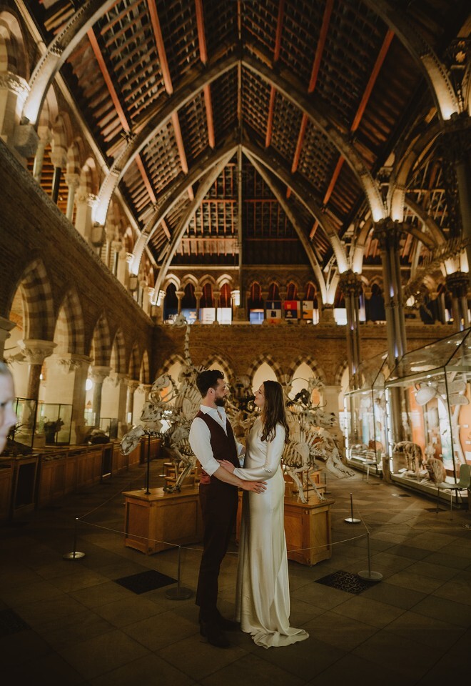Wedding couple standing together inside the Oxford University Museum of Natural History, captured by V & H Photography.