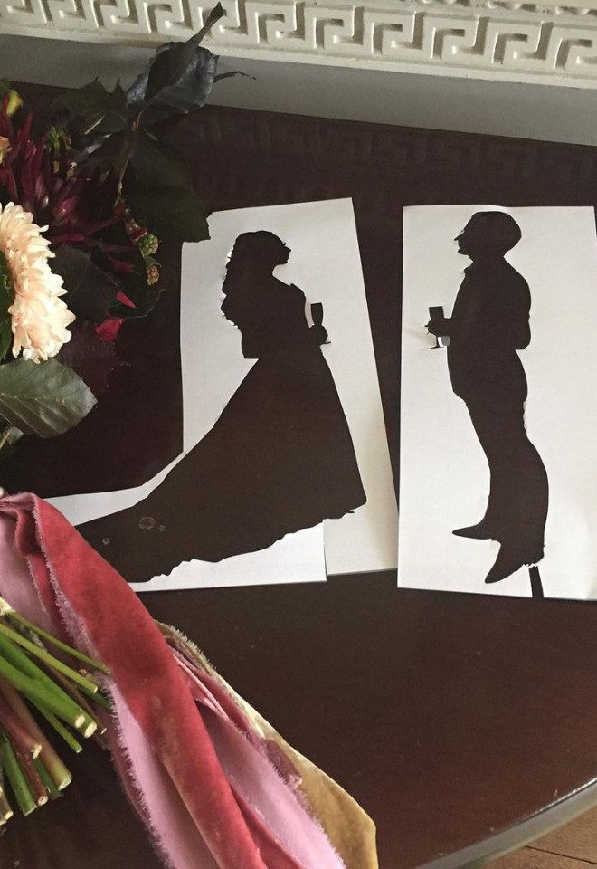 Silhouettes of bride and groom next to a floral display