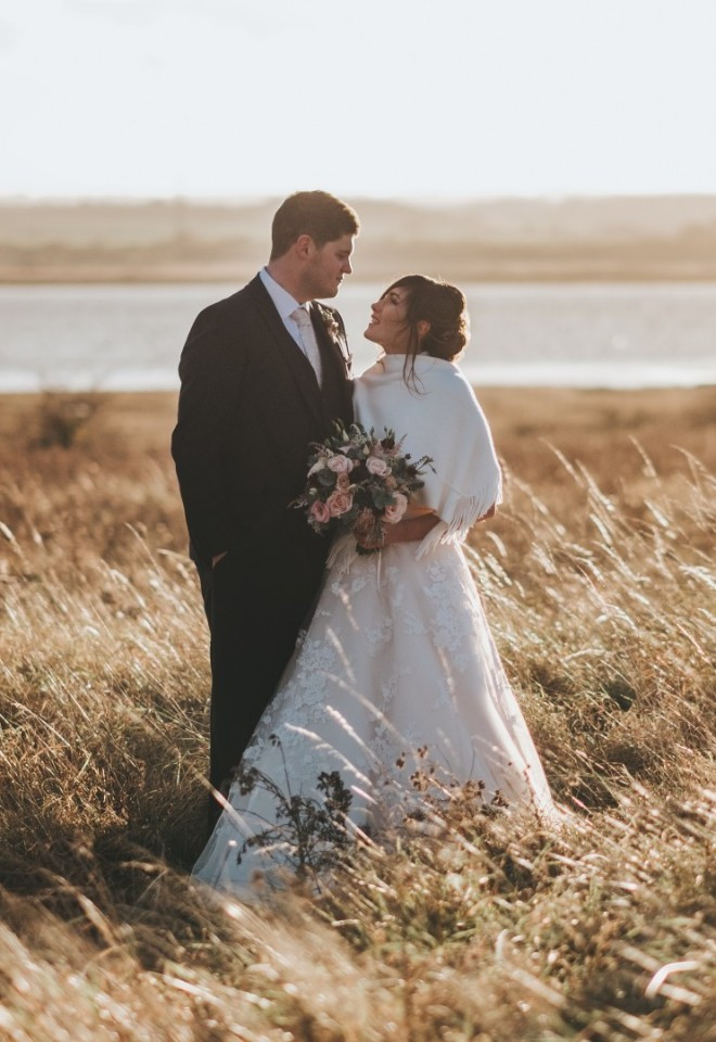 Bride and groom in golden grasses, in front of the Kent estuary