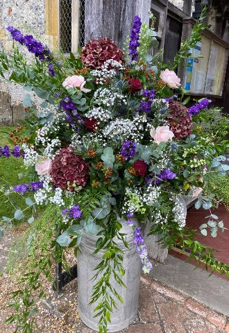 milk urn wedding floral display of purple, burgundy, and blush roses and delphiniums with hints of eucalyptus and babies breath by ann laing flowers, oxfordshire