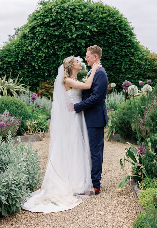 Bride and Groom standing in the Kitchen Garden at South Farm Barn wedding venue in Cambridgeshire