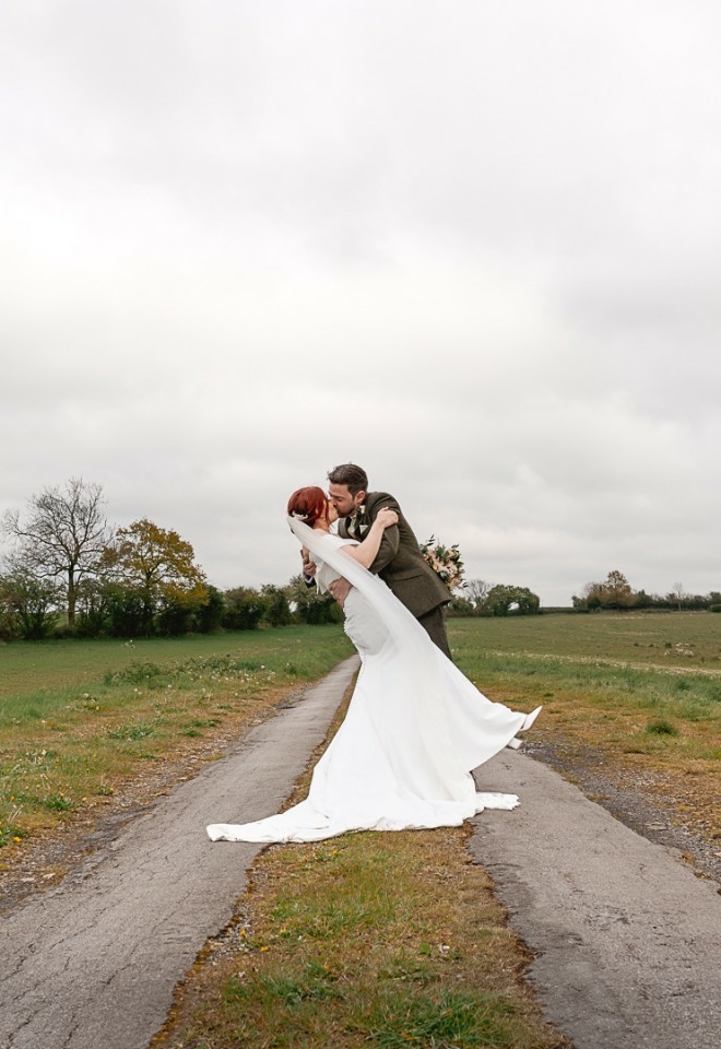 Dramatic dip portrait of bride and groom in the middle of field