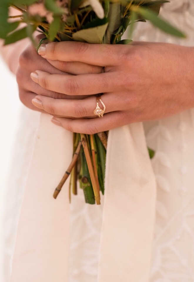 A vintage style gold wedding and engagement ring on a b rides hand as she holds her bouquet on her wedding day