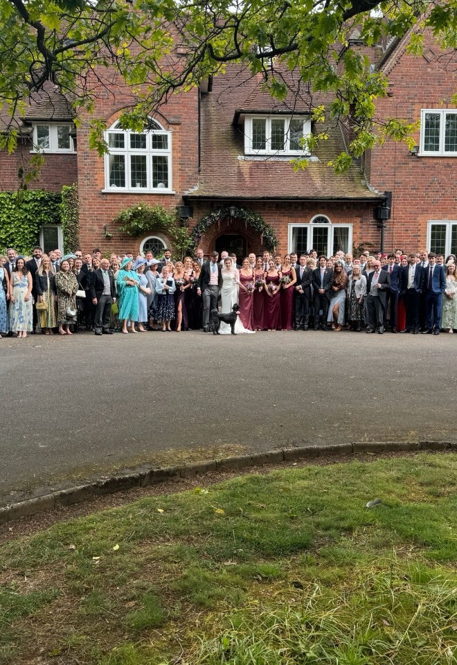 Bride and groom celebrating with wedding guests outside a luxury country house wedding venue, posing for a group photograph in the UK countryside