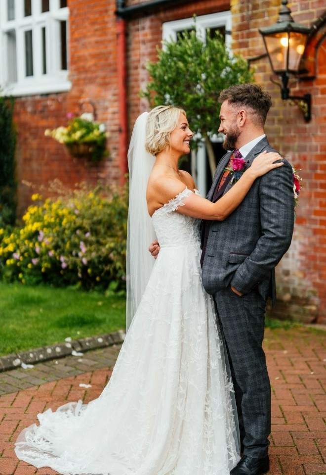 Newlyweds stood together outside the Manor door, smiling at each other- Sprowston Manor Norwich