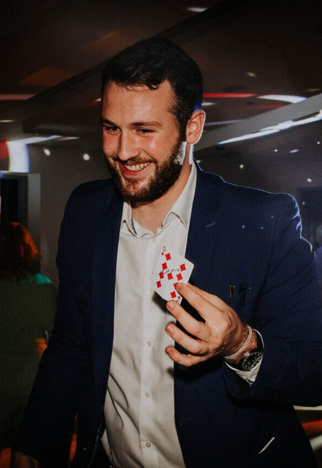 Magician Revilo Twist Magic does a card trick at the evening reception party of the wedding