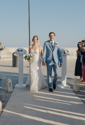 bride and groom walk down the aisle surrounded by their family and friends at the wedding in cyprus