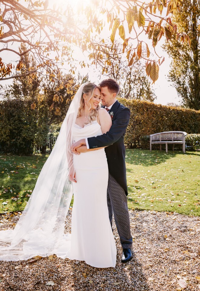 Bride and groom embracing in warm sunshine during golden hour at Merriscourt wedding venue