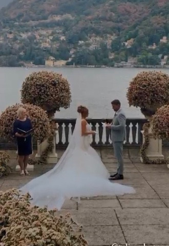 Bride and groom exchanged vows on a terrace overlooking Lake Como with a celebrant officiating the wedding standing to the side of the couple.