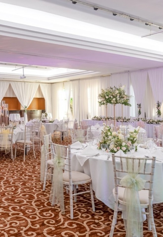 Wedding reception set-up at Grand Hotel Gosforth Park with round dining tables, blossom centrepieces and draped white ceremony suite.
