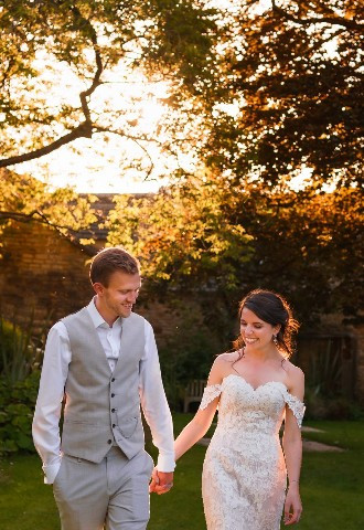 Bride and groom walking hand in hand at golden hour for their wedding photography at The Bay Tree Hotel, Burford, Oxfordshire