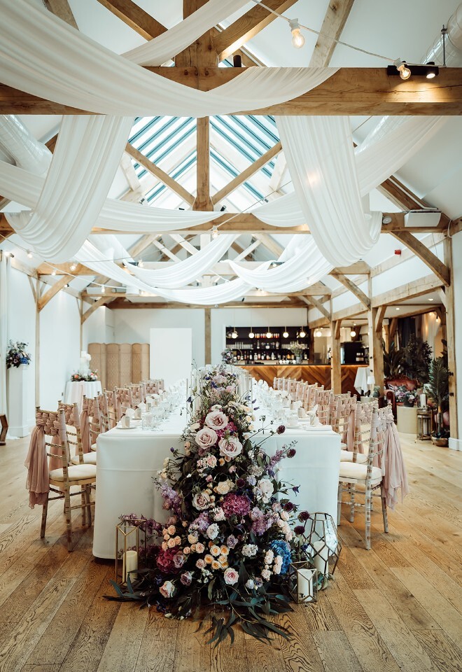Interior of wedding barn at Alfriston Gardens set for a long tressel table wedding breakfast