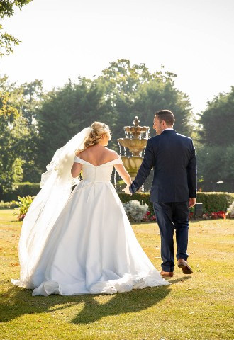 bride and groom walk hand in hand towards the fountain at The Lawn wedding venue, Rochford, Essex