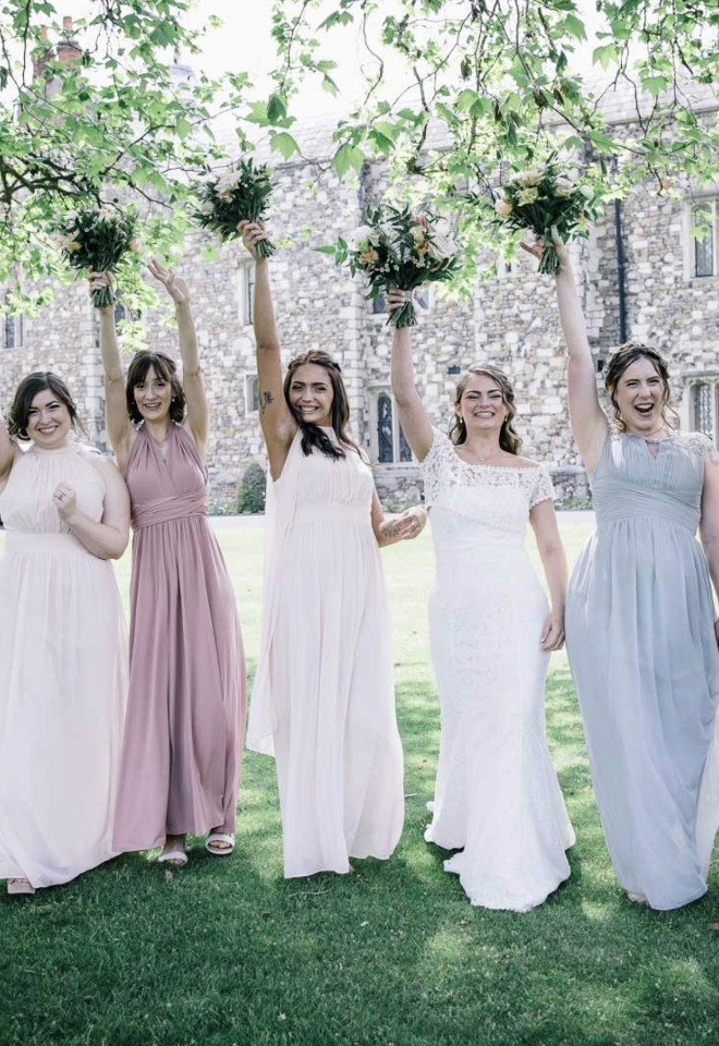 Bride & bridesmaids with their wedding bouquets being held in the air outside Hall Place & Gardens in Bexley, Kent. summer wedding, pastel coloured bridesmaids dress and white bridal gown. 