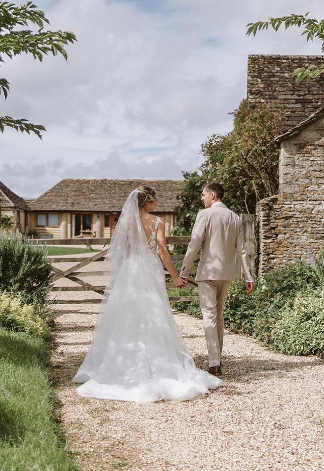 bride and groom holding hands wedding ceremony at The Great Tythe Barn in Gloucestershire