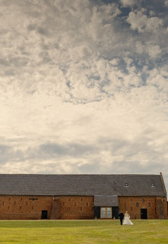 Wedding couple in the grounds walking towards Copdock Hall barn Suffolk