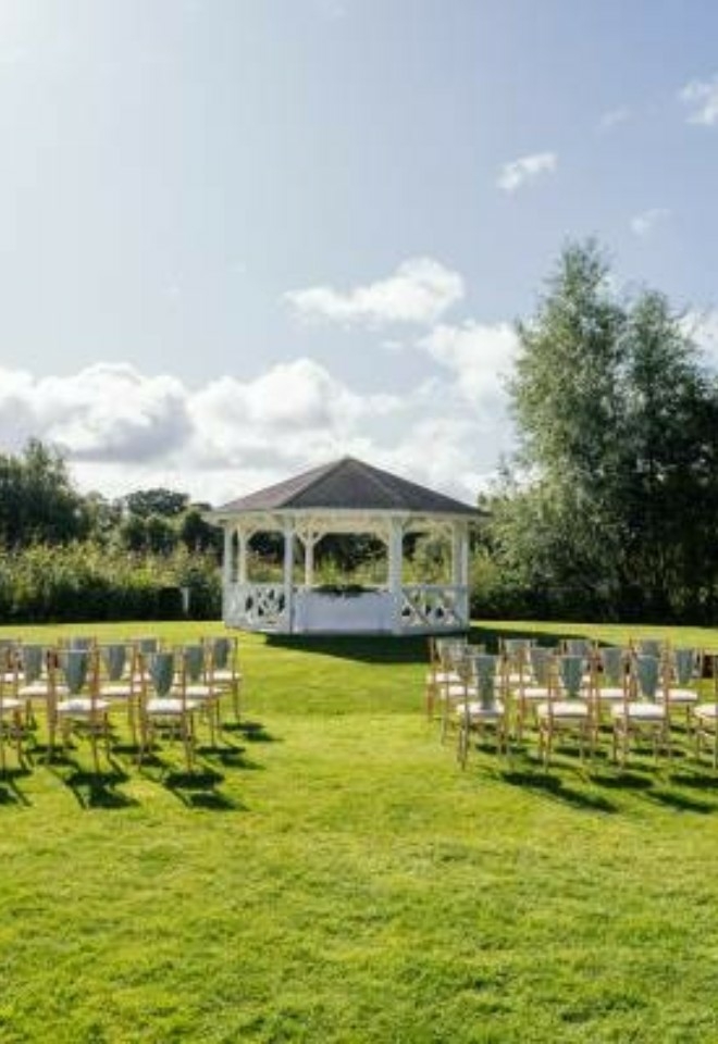 View of a ceremony set up outside the Pagoda with trees and sun in the background- Sprowston Manor Norwich