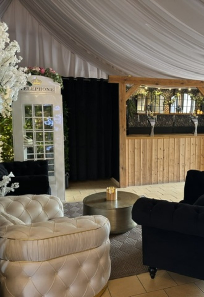 Wedding lounge area at Duvale Priory in Tiverton, Devon, featuring stylish seating, floral décor, a rustic wooden bar and elegant draped ceiling.