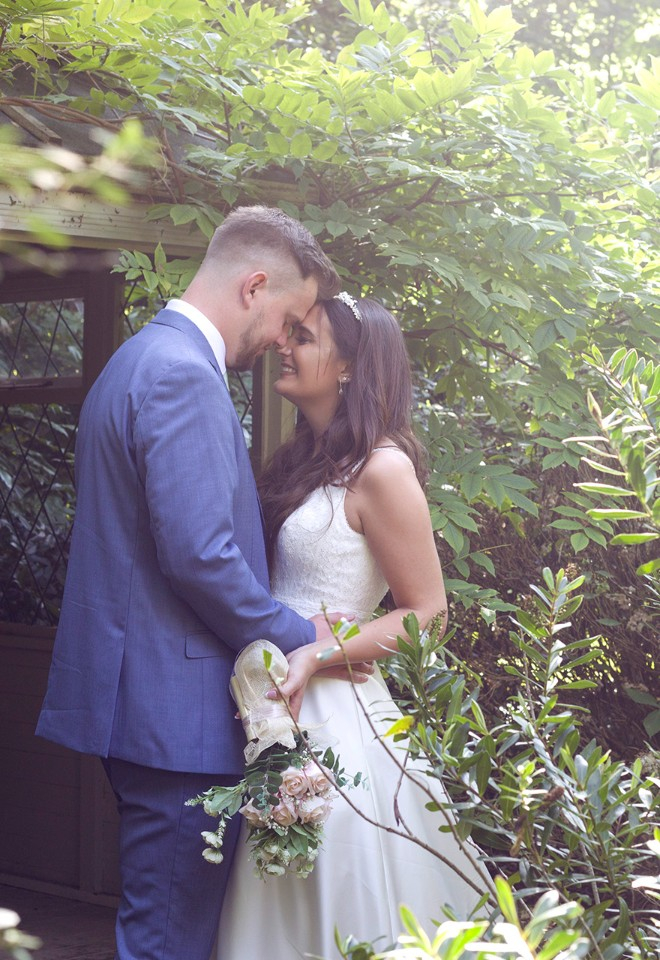 a gorgous couple embrace, surrounded by greenery in the secret garden at The Old Vicarage. 