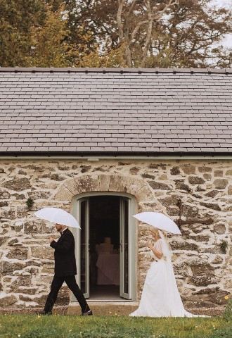 Bride and groom walking in the rain at Henblas Country Park, Anglesey, North Wales