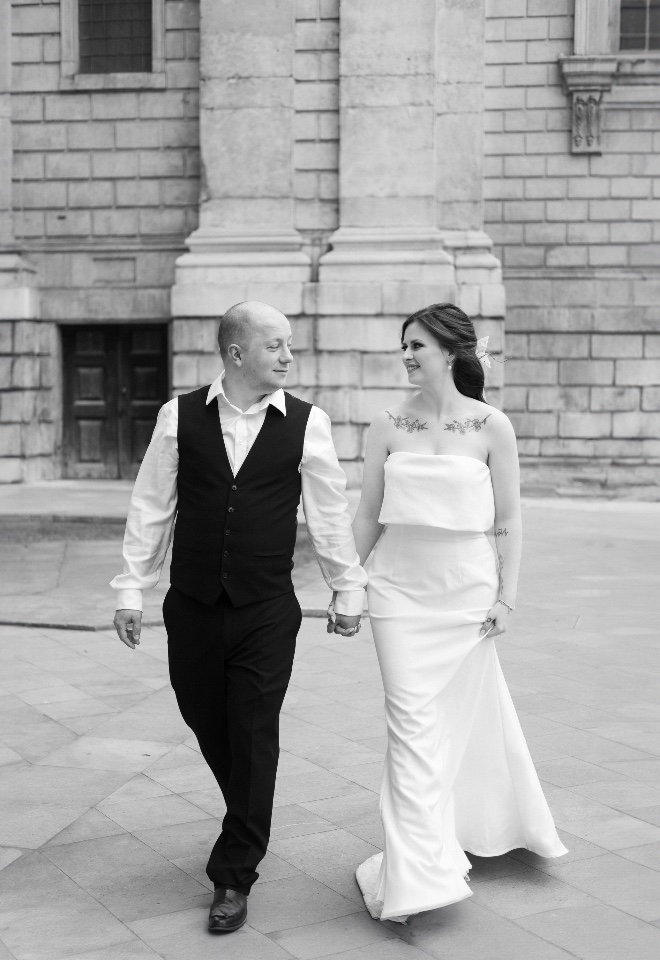 A black and white image of a bride and groom walking through London 