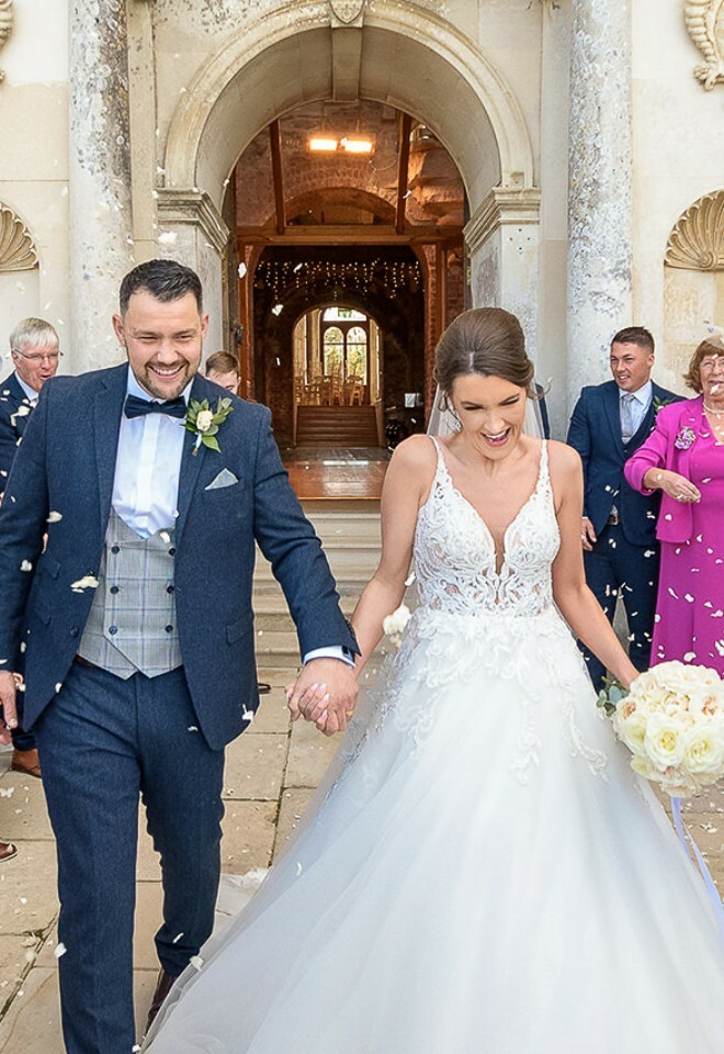 bride & groom just married coming out of venue with confetti being thrown at them. dorset wedding photographer