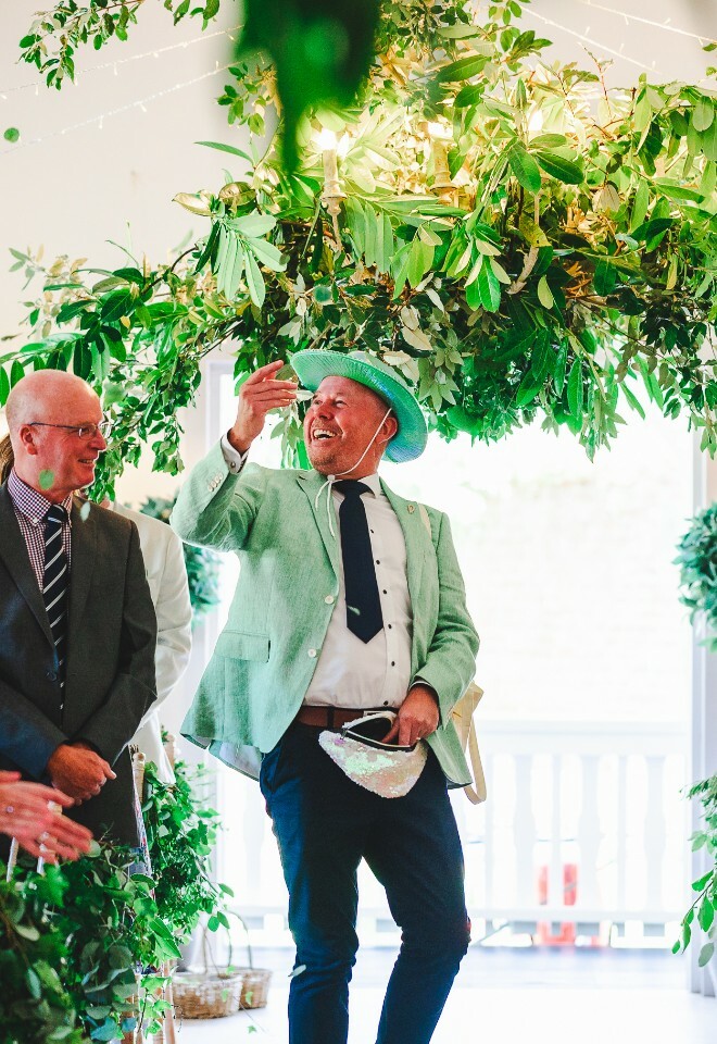 groomsman throwing confetti down aisle