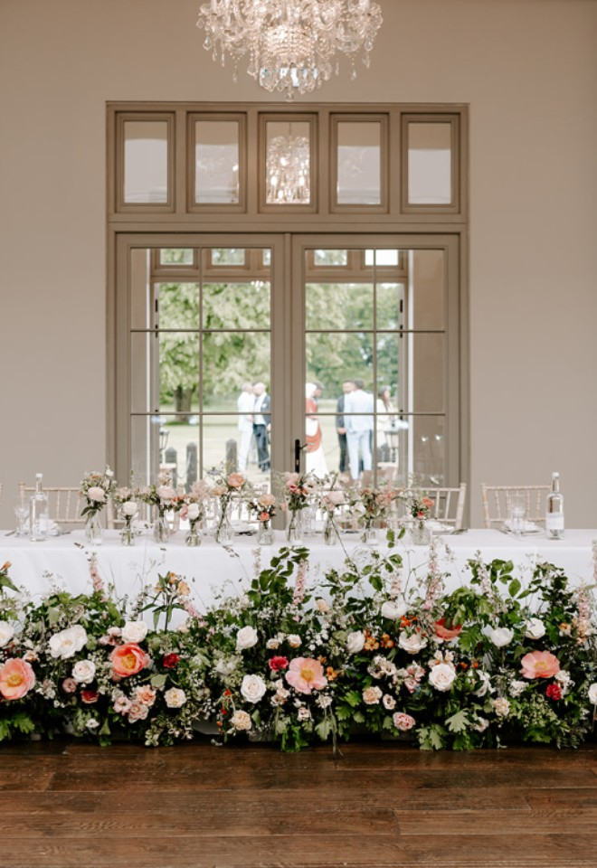 Floral meadow design bordering the head table at Offley Place with bud vases above