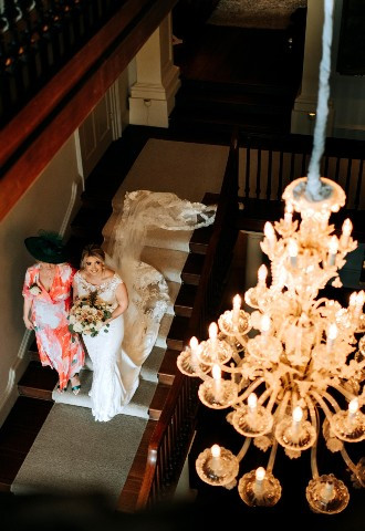 Bride and her mother walking down the staircase at Howsham Hall, Yorkshire