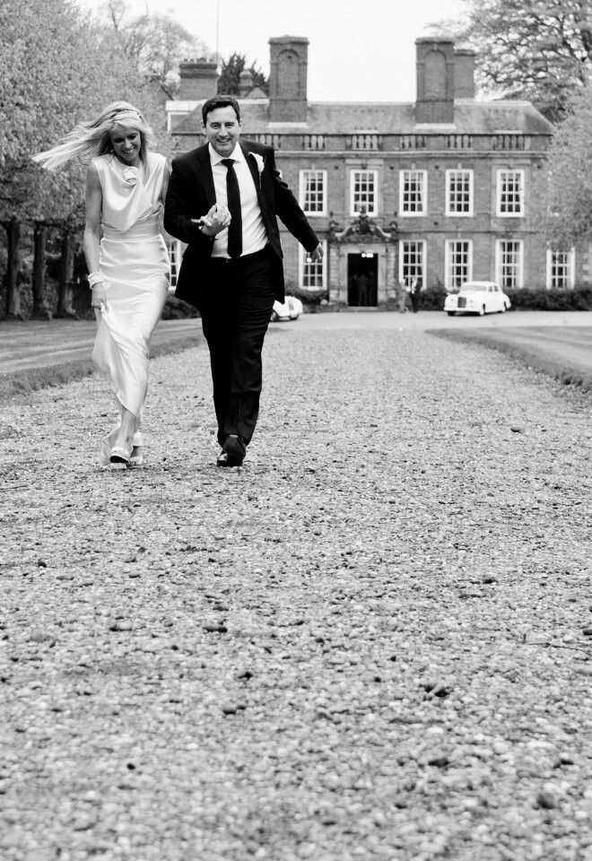 Black and white image of bride and groom walking away from the wedding venue and reception