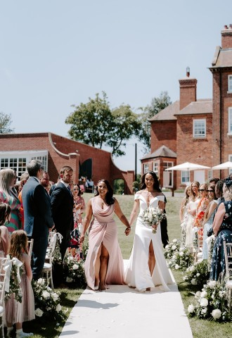 Bride and bridesmaid holding hands walking down the aisle