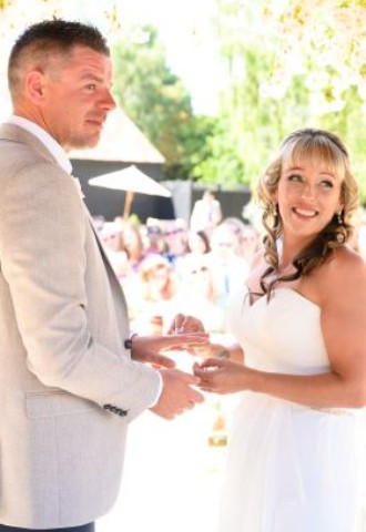 bride and groom holidng hands looking back at celebrant during vows