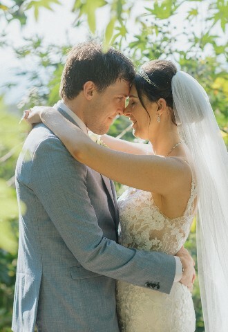 bride and groom pose for their wedding pictures surrounded by lush green foliage