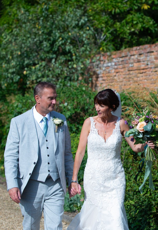 Newlywed couple walk in the walled garden at Stapleford Park, Leicestershire. 