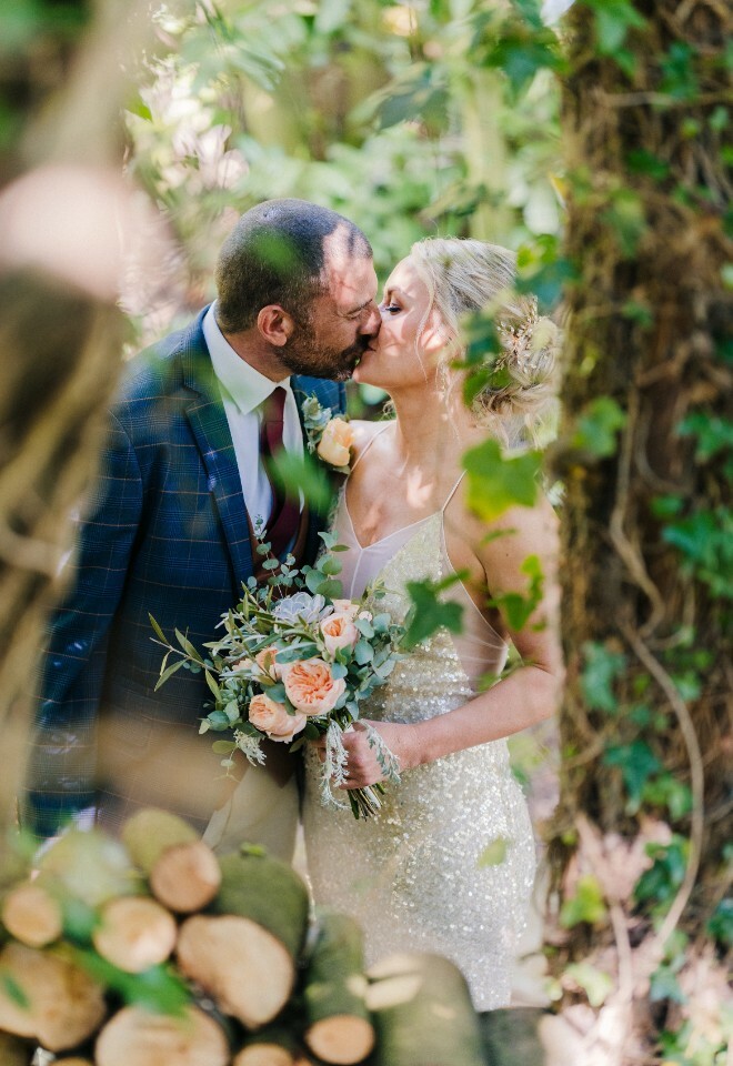 Bride and groom kissing between trees