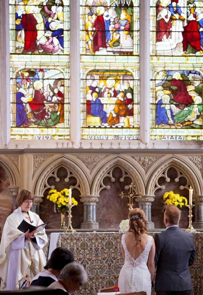 bride and groom in front of stained glass window, Northamptonshire wedding photographer