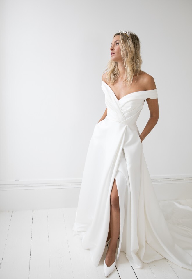 Off the shoulder satin wedding dress with split and ruched bodice. Available at Your Story Bridal, Marlow.