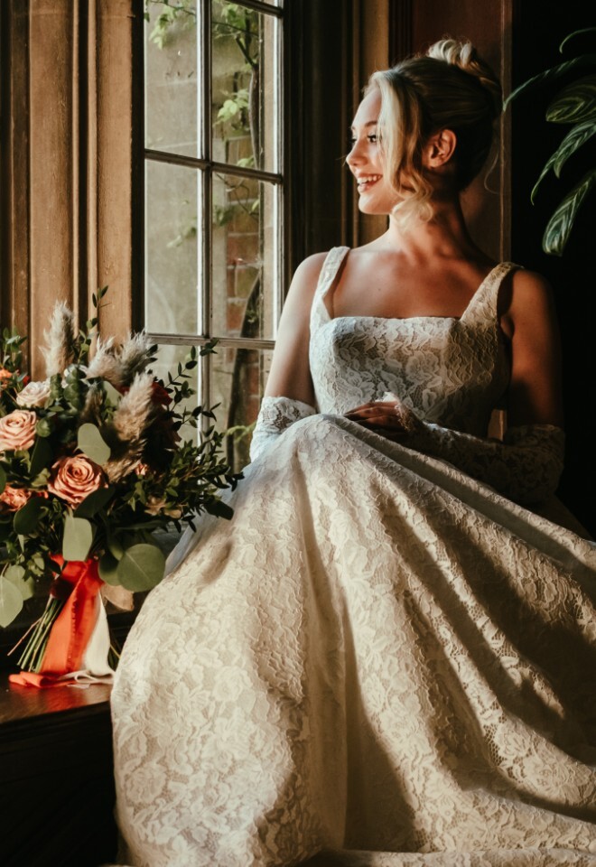 Bride sat by window with flowers